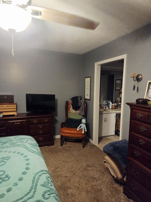 bedroom featuring light tile patterned flooring, light colored carpet, ensuite bath, and a ceiling fan