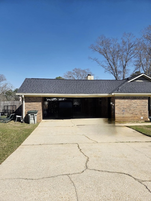 view of home's exterior with driveway, fence, roof with shingles, brick siding, and a chimney