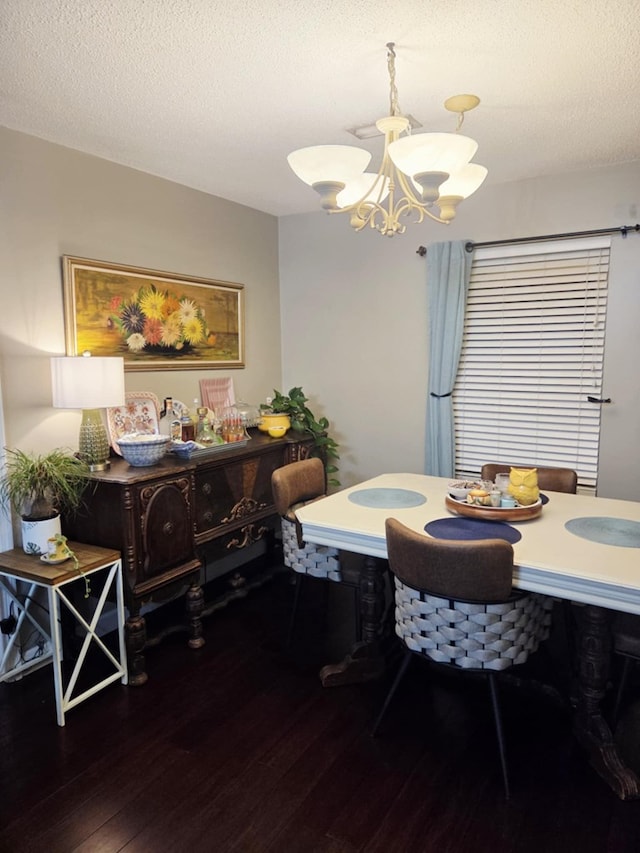 dining area with a textured ceiling, a notable chandelier, and hardwood / wood-style flooring