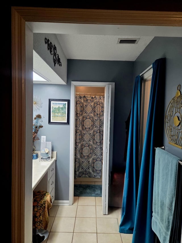 bathroom featuring tile patterned floors, visible vents, a textured ceiling, baseboards, and vanity