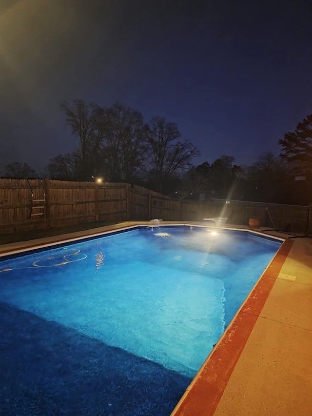 pool at night featuring a fenced in pool and a fenced backyard