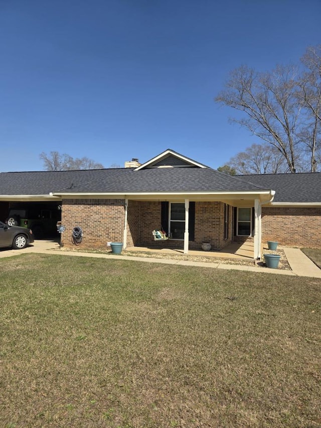 view of front of home featuring brick siding, an attached carport, and a front yard