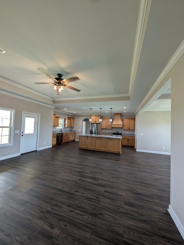 12589 Fortner St, Newton, AL 36352 - unfurnished living room featuring baseboards, dark wood finished floors, ornamental molding, a tray ceiling, and ceiling fan