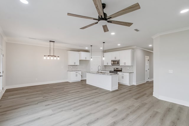 kitchen featuring decorative light fixtures, white cabinetry, decorative backsplash, stainless steel appliances, and a center island with sink