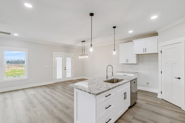 kitchen featuring pendant lighting, white cabinetry, sink, stainless steel dishwasher, and light stone counters