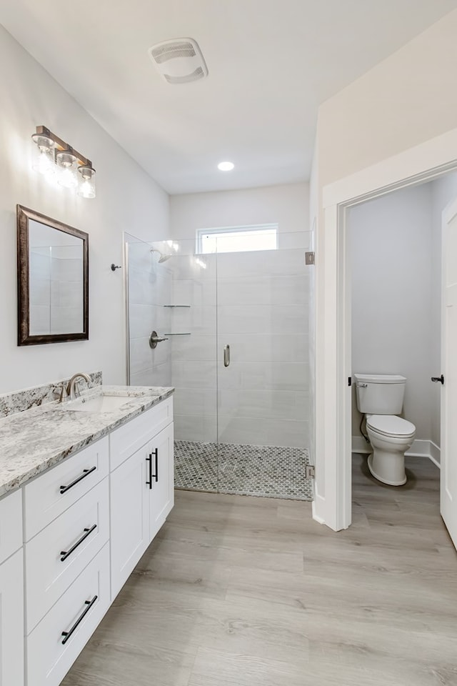 bathroom featuring walk in shower, vanity, toilet, and hardwood / wood-style flooring