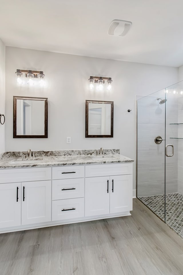 bathroom featuring vanity, hardwood / wood-style flooring, and a shower with door