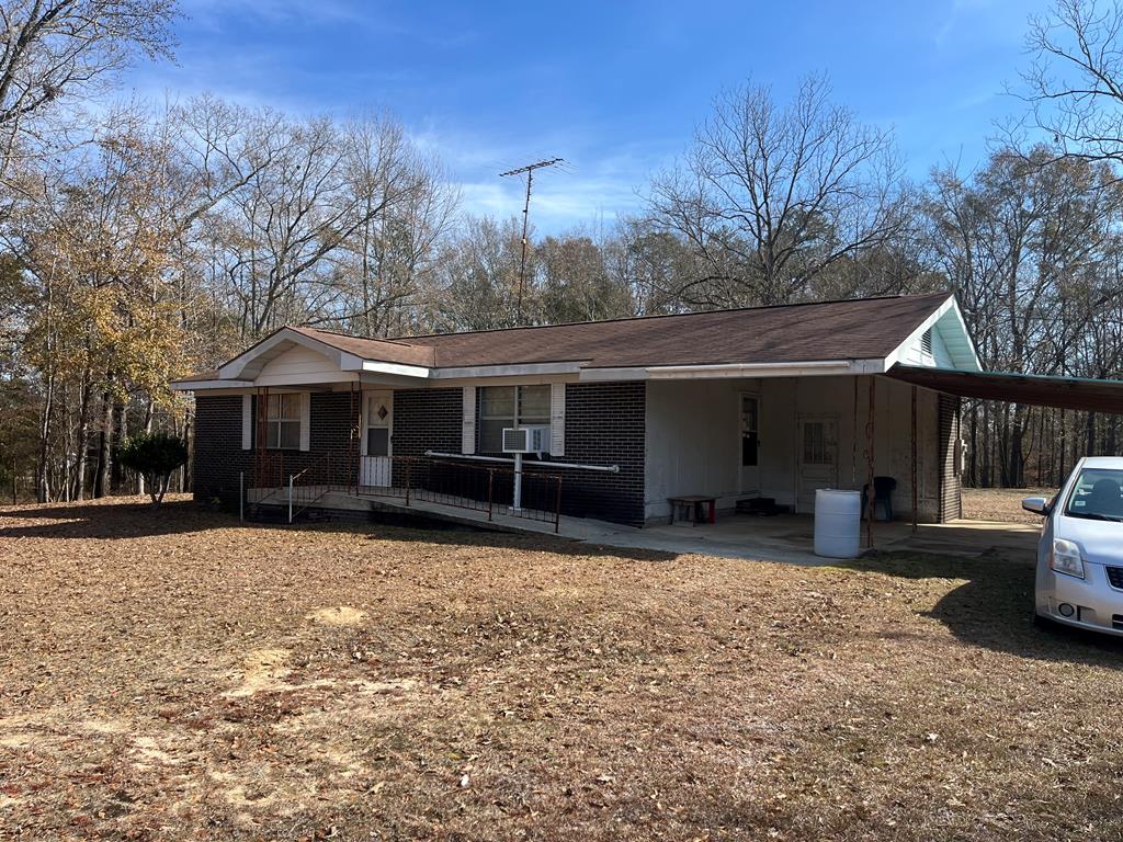 ranch-style home featuring cooling unit, a carport, and a porch