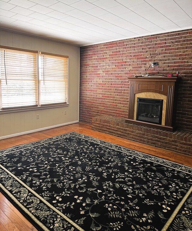 living room featuring a fireplace, hardwood / wood-style flooring, and brick wall