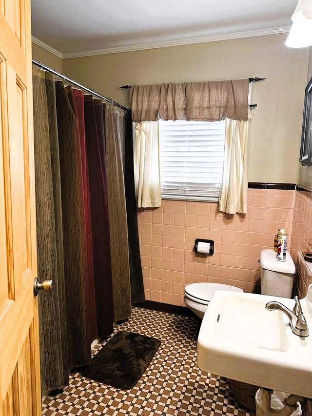 bathroom featuring toilet, sink, crown molding, and tile walls