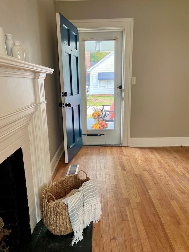 entryway with wood-type flooring and a brick fireplace