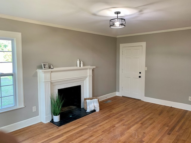 unfurnished living room with hardwood / wood-style floors, crown molding, and a brick fireplace