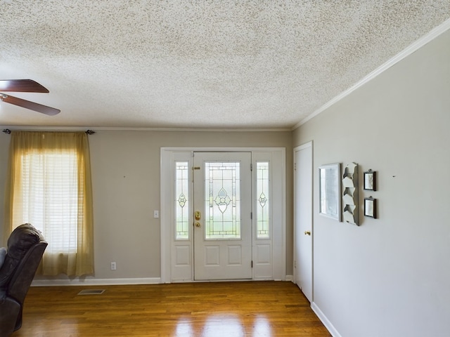 foyer with crown molding, visible vents, plenty of natural light, and wood finished floors