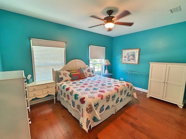 bedroom with visible vents, baseboards, a ceiling fan, and dark wood-style flooring