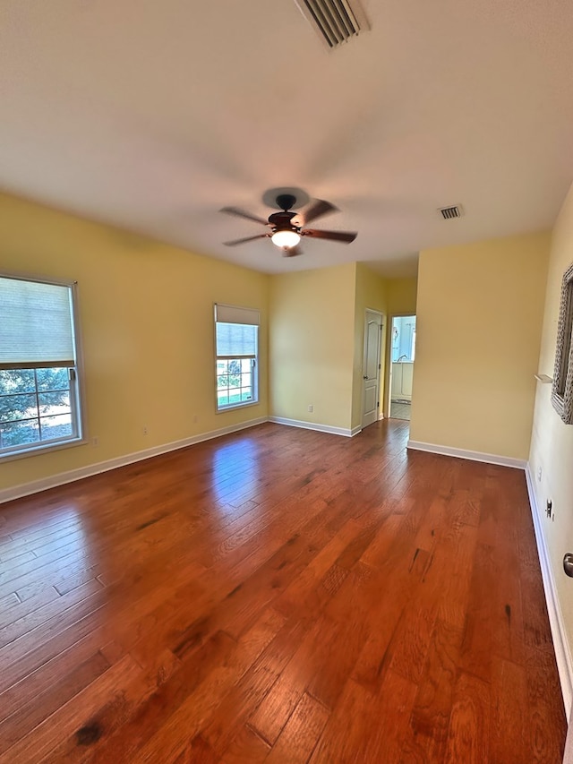 spare room featuring visible vents, baseboards, dark wood finished floors, and a ceiling fan