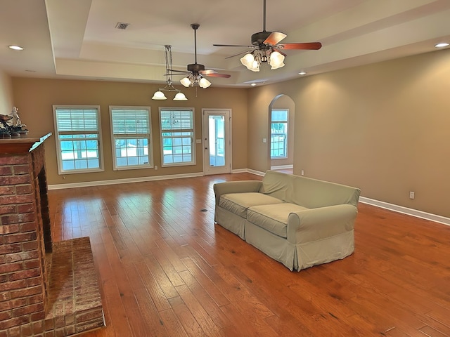 living area featuring hardwood / wood-style floors, visible vents, baseboards, a tray ceiling, and recessed lighting