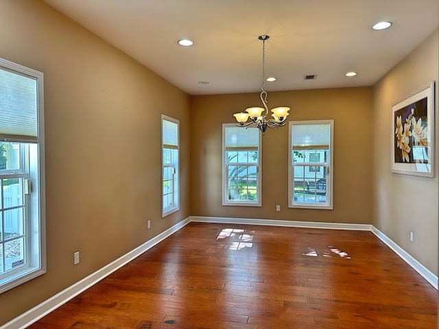 spare room featuring a notable chandelier, recessed lighting, baseboards, and wood-type flooring