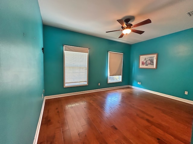 unfurnished room with visible vents, baseboards, hardwood / wood-style floors, and a ceiling fan