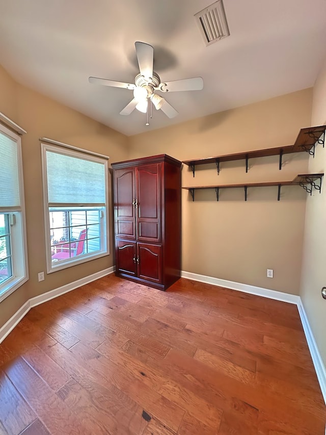 unfurnished bedroom with ceiling fan, visible vents, baseboards, and wood finished floors