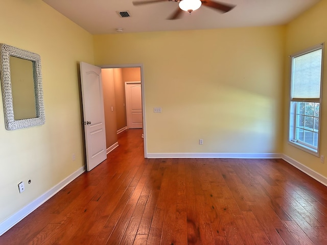 spare room featuring a ceiling fan, baseboards, visible vents, and dark wood-style flooring