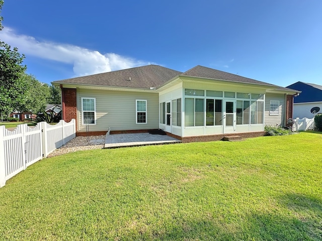 rear view of house featuring a yard, a patio area, a fenced backyard, and a sunroom