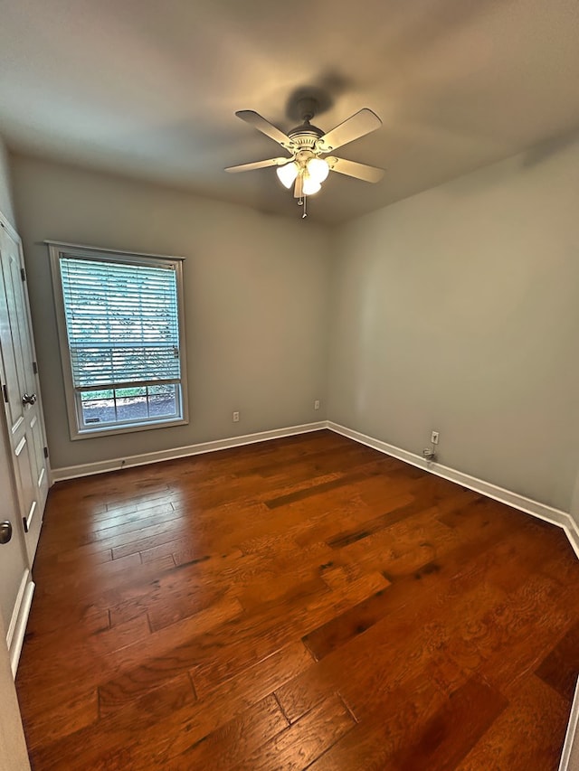 empty room with dark wood-style floors, baseboards, and ceiling fan