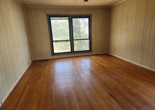 empty room featuring wooden walls and hardwood / wood-style flooring