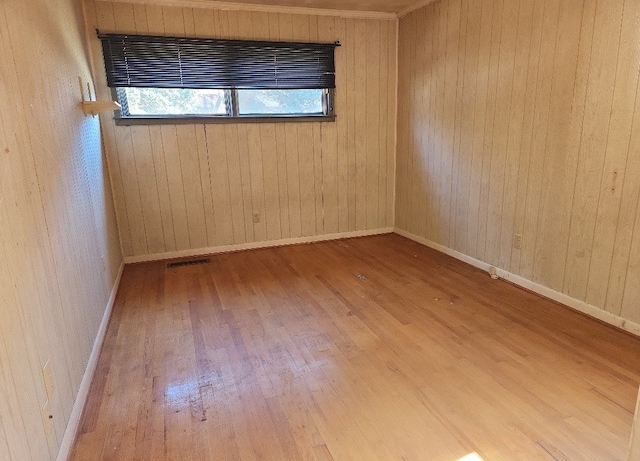 empty room featuring wooden walls and hardwood / wood-style flooring