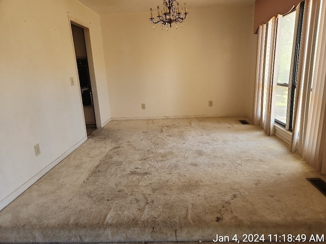 spare room with light carpet and a notable chandelier