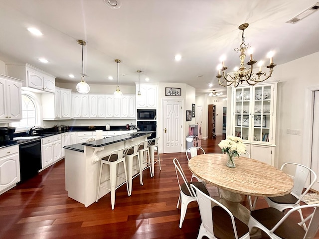 403 Stonegate Dr, Dothan, AL 36305 - kitchen featuring black appliances, a breakfast bar area, dark countertops, a chandelier, and a center island