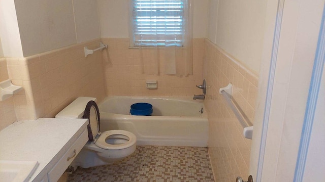 bathroom with tile walls, toilet, a bathtub, and a wainscoted wall