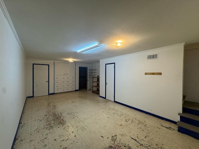 empty room with baseboards, visible vents, a textured ceiling, crown molding, and tile patterned floors