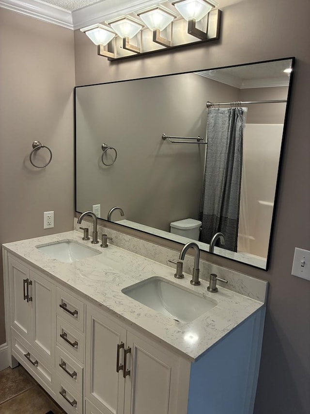 bathroom with double vanity, toilet, ornamental molding, and a sink
