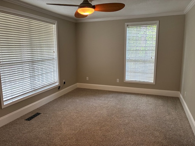 spare room with ceiling fan, crown molding, visible vents, baseboards, and carpet floors