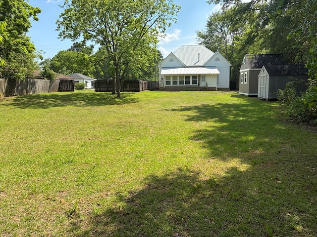 view of yard with fence, a storage unit, and an outdoor structure