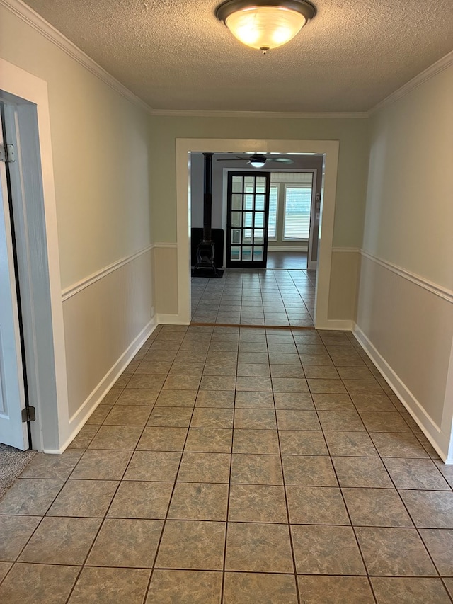 corridor with a textured ceiling, tile patterned flooring, and wainscoting