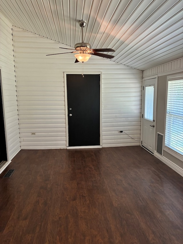 interior space featuring wood walls, visible vents, a ceiling fan, and dark wood finished floors