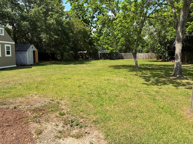 view of yard with fence, a shed, and an outbuilding