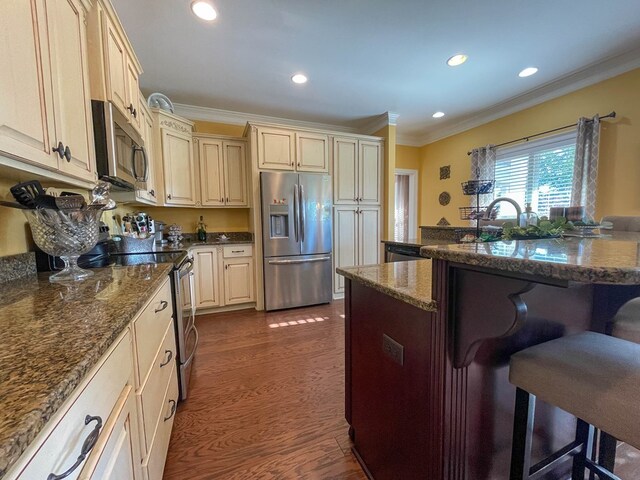 1621 Adkinson Rd, Newton, AL 36352 - kitchen with appliances with stainless steel finishes, a kitchen breakfast bar, crown molding, dark wood-type flooring, and cream cabinets
