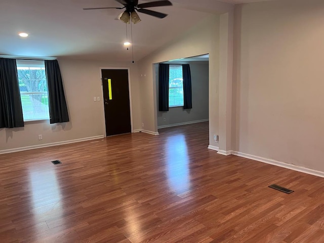 unfurnished room with lofted ceiling, a wealth of natural light, dark wood-type flooring, and ceiling fan