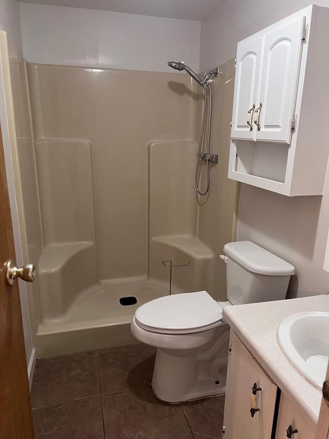 bathroom with tile patterned flooring, toilet, a shower, and vanity