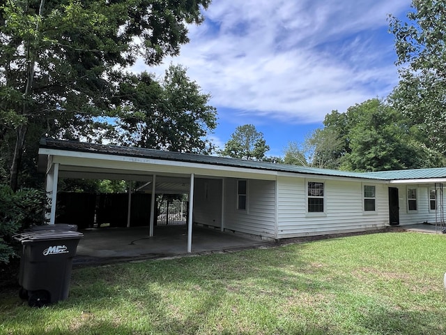 rear view of property with a carport and a lawn