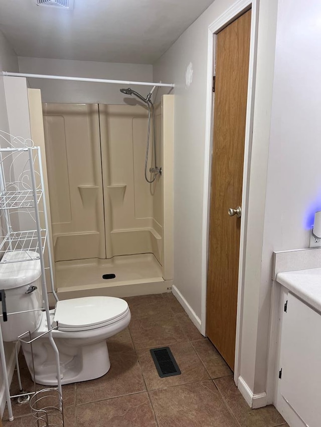 bathroom featuring a shower, vanity, tile patterned flooring, and toilet