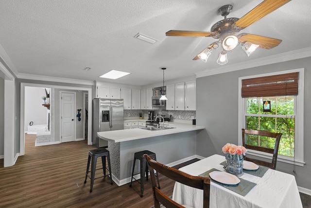 102 Lindsey Ln, Dothan, AL 36305 - kitchen with stainless steel appliances, a peninsula, light countertops, a kitchen bar, and dark wood finished floors