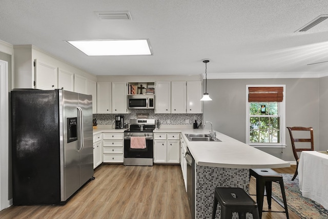 102 Lindsey Ln, Dothan, AL 36305 - kitchen featuring stainless steel appliances, a sink, a peninsula, light wood-style flooring, and crown molding