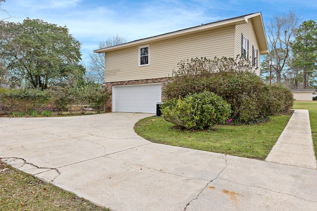 view of home's exterior featuring brick siding, an attached garage, driveway, and a lawn