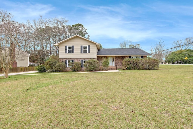 tri-level home with brick siding, a front lawn, and fence