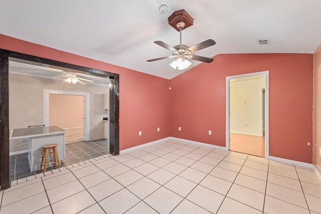 spare room featuring ceiling fan, light tile patterned floors, and vaulted ceiling