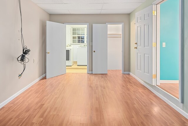 unfurnished bedroom with independent washer and dryer, a paneled ceiling, light hardwood / wood-style floors, and a closet