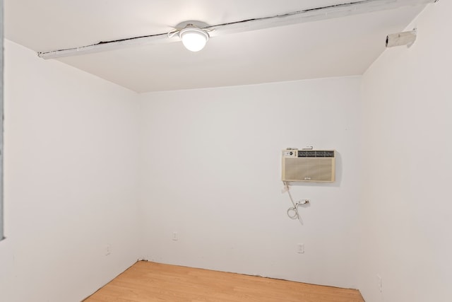 clothes washing area with a wall mounted AC and hardwood / wood-style flooring